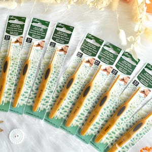 May include: A collection of crochet hooks with yellow handles and black grips, displayed on their original packaging. The hooks range in size from 2.0mm to 6.0mm. The packaging includes the text "Soft Touch Crochet Hook".