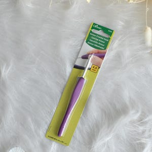 May include: A Clover Amour Crochet Hook, size 4.0 mm, with a purple handle and a silver hook. The hook is packaged on a green and yellow card with the product name and brand information.