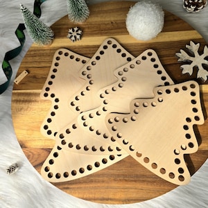 May include: A set of light-coloured wooden cutouts shaped like Christmas trees, each featuring a series of evenly spaced holes along the perimeter, designed for crafting or crochet projects, arranged in an overlapping stack on a round wooden board.