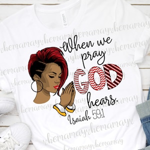 May include: White t-shirt with a red and white striped design that says "When we pray God hears. Isaiah 59:1". A black woman with red hair is praying in the design.