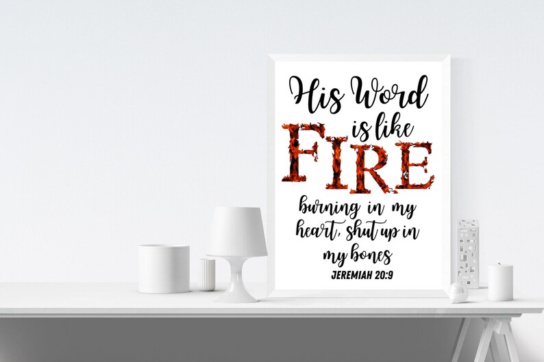 May include: A white framed print with the text "His Word is like FIRE burning in my heart, shut up in my bones JEREMIAH 20:9". The word "FIRE" is in large, bold letters and is stylized with a fiery orange and red design.