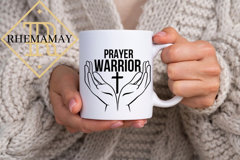 May include: White ceramic mug with a black design of two hands holding a cross with the text "PRAYER WARRIOR" above the cross.