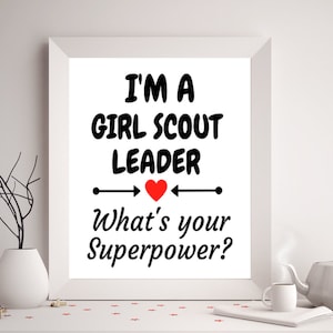 K&ouml;nnte beinhalten: Ein wei&szlig;er gerahmter Druck mit schwarzem Text, der "Ich bin eine Girl Scout Leader. Was ist deine Superkraft?" lautet, mit einem roten Herzen in der Mitte.