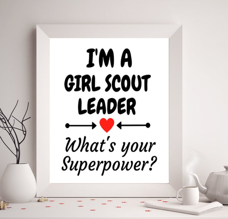 K&ouml;nnte beinhalten: Ein wei&szlig;er gerahmter Druck mit schwarzem Text, der "Ich bin eine Girl Scout Leader. Was ist deine Superkraft?" lautet, mit einem roten Herzen in der Mitte.