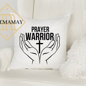 May include: White throw pillow with black text that reads "Prayer Warrior" and a black cross. The text is surrounded by two black hands in a praying position.