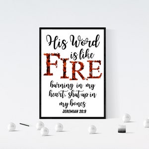 May include: A black and white framed print with the text "His Word is like FIRE burning in my heart, shut up in my bones JEREMIAH 20:9". The word "FIRE" is in large letters and is made up of a red and orange flame design.