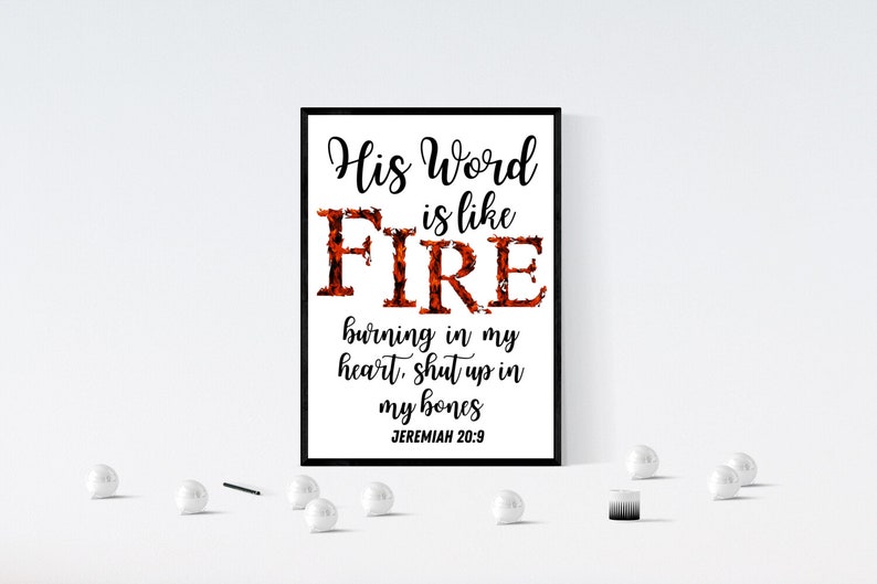 May include: A black and white framed print with the text "His Word is like FIRE burning in my heart, shut up in my bones Jeremiah 20:9". The word "FIRE" is in large letters and is made up of a red and orange flame design.