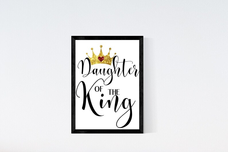 May include: A black framed print with a white background. The print features a gold glitter crown with a red heart in the center and the text "Daughter of the King" in black cursive.