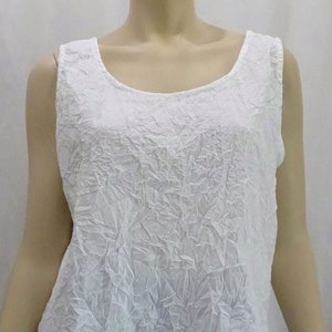 May include: White sleeveless top with a crinkled texture. The top has a scoop neckline and is made of a lightweight fabric.
