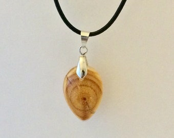 May include: A wooden pendant with a natural wood grain pattern, shaped like a teardrop, hangs from a black leather cord. The pendant has a silver bail.