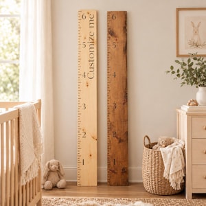 May include: Two vertical wooden growth charts leaning against a wall. The left board is light-colored wood with black markings from 1 to 6 and the text Customize me. The right board is dark-stained wood with black markings from 1 to 6.