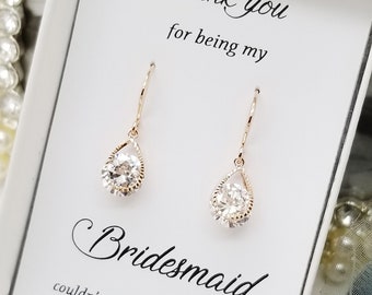 May include: A pair of rose gold teardrop earrings with clear faceted stones, presented on a white card with black text that reads Thank you for being my Bridesmaid, couldn't say I do without you.