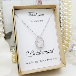 May include: A white card with the text "Thank you for being my Bridesmaid couldn't say "I do" without You" and a silver necklace with a teardrop-shaped pendant in a brown box.