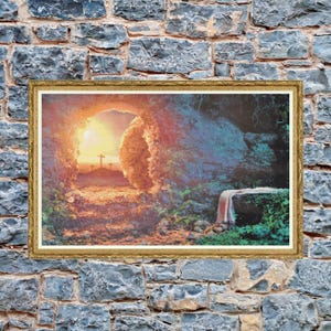 May include: A framed print showing a sunrise over a path leading to three crosses. The path is framed by a stone archway. The print is in a gold frame and is mounted on a gray stone wall.