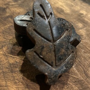 May include: Two dark brown leaf-shaped wooden napkin rings.
