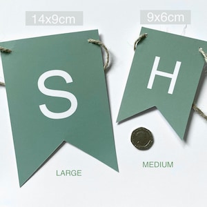 Op de afbeelding: Een groene vlag van vilt met de letters "SH" in wit. De vlag is verkrijgbaar in twee maten: 14x9cm (groot) en 9x6cm (medium).