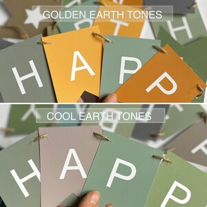 Op de afbeelding: Een banner met het woord "HAPPY" gespeld in witte letters op groen en bruin karton. De banner is versierd met een ster en de woorden "Golden Earth Tones" en "Cool Earth Tones".