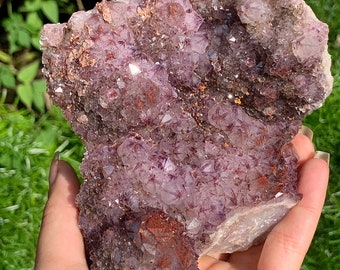 Op de afbeelding: Een grote amethistcluster met een paars en wit kleurenschema. De amethist heeft een natuurlijke, ruwe textuur en is bedekt met kleine kristallen. De cluster heeft een diameter van ongeveer 15 cm.