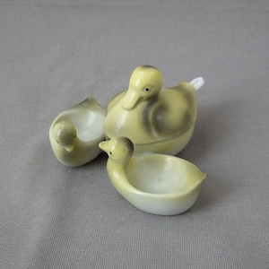 Könnte beinhalten: Drei Keramik-Entenfiguren, eine größere Ente mit Deckel und zwei kleinere Enten. Die Enten sind gelb mit braunen Markierungen.