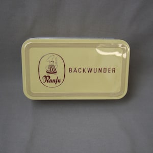 Könnte beinhalten: Eine gelbe rechteckige Dose mit braunem Rand und den aufgedruckten Worten "Backwunder" und "Ranja". Im Logo ist ein Cartoon-Koch abgebildet.