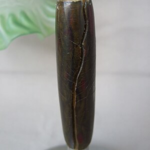 Op de afbeelding: Een lamponderdeel met een cilindervormige, donkerbruine handgreep met een gemarmerde textuur en een verticale barst in het midden, gemonteerd op een zilverkleurige metalen stang boven een ronde voet met een kleine witte drukknopschakelaar.