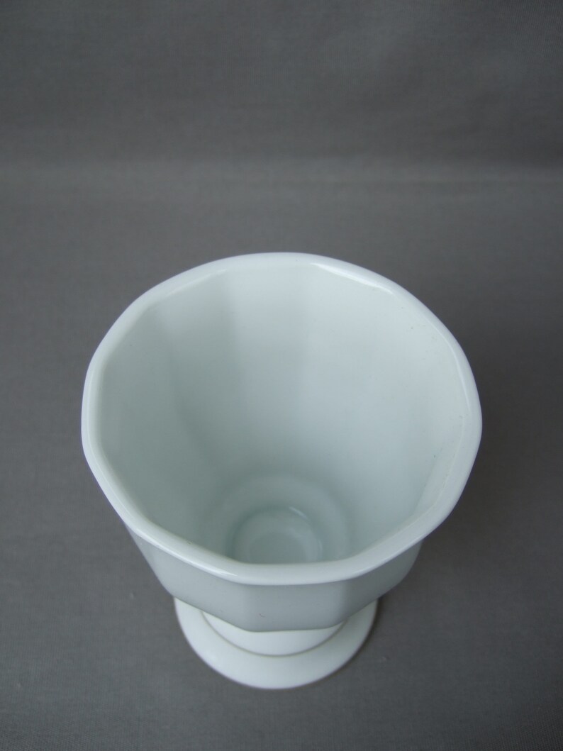 K&ouml;nnte beinhalten: Wei&szlig;e Keramikvase mit geriffeltem Design und einem Sockel.