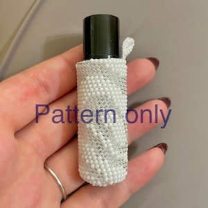 May include: A white beaded bottle cover with a black lid and a small white loop. The cover is made of small white beads and has a silver thread running through it. The text "Pattern only" is visible in the image.