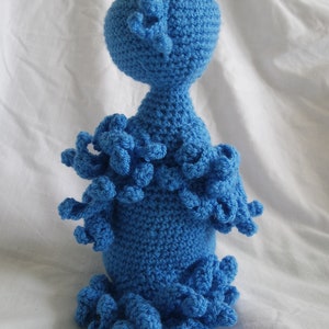 Puede incluir: Un juguete de pulpo azul de crochet con una cabeza redonda y muchos tent&aacute;culos.