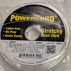 May include: A spool of clear stretchy bead cord, labeled "POWERCORD® Stretchy Bead Cord". The label also states "Latex-free", "No Fray", "Knots Easily", "Color: Clear", "Size: .8mm", "Length: 25m", and includes a cautionary statement about the product not being a toy and not intended for use by children under 14. A barcode and QR code are also included on the label.