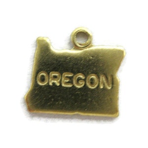 May include: Gold-colored metal charm shaped like the state of Oregon with the word "OREGON" inscribed on the charm.
