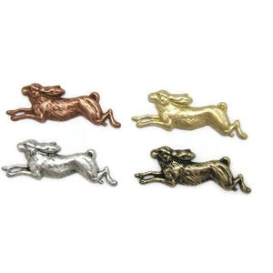 May include: Four metal hare charms in different finishes: copper, gold, silver, and antique gold. Each charm features a detailed design of a running hare.