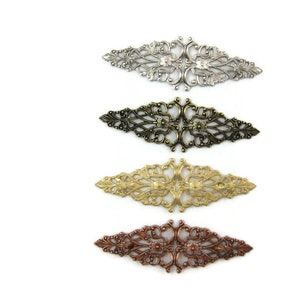 May include: Four ornate metal embellishments in different finishes: silver, bronze, gold, and copper. Each embellishment features a delicate, intricate design with a floral motif.