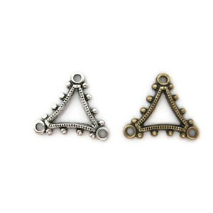 May include: Two triangle-shaped metal connector charms, one silver and one gold, with decorative beading around the edges and three loops for attaching jewelry.