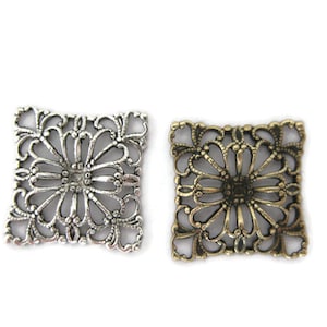 May include: Two square metal filigree embellishments, one silver and one antique gold, with a floral design.
