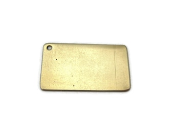May include: A blank brass tag with a hole at the top. The tag is rectangular and has a slightly textured surface.