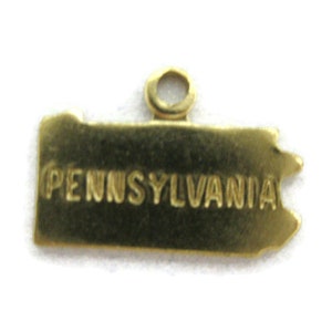 May include: Gold-colored charm shaped like the state of Pennsylvania with the word "PENNSYLVANIA" inscribed on it.