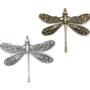 May include: Two ornate dragonfly charms, one silver and one gold, with intricate details and a dangling body.