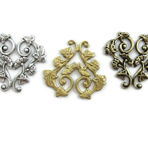 May include: Three ornate metal heart-shaped embellishments with a floral design. The embellishments are silver, gold, and antique gold.