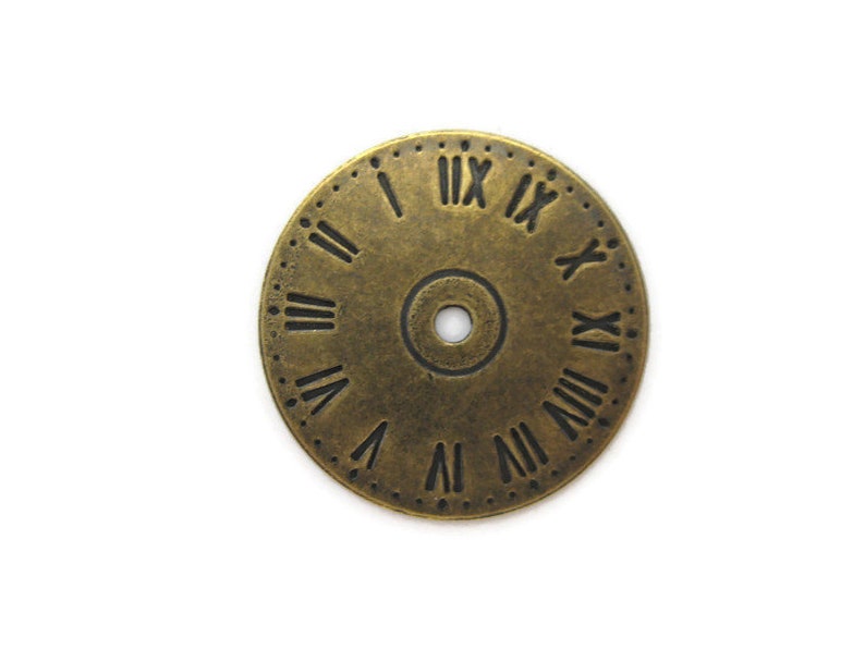 May include: A gold-toned metal clock face with Roman numeral markings. The clock face has a small hole in the center.