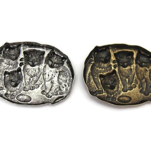 Peut inclure: Une broche ovale en argent et or avec un motif de quatre chatons jouant avec une balle. Les chatons sont en relief et la broche a une finition lisse et polie.