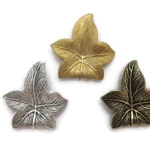 May include: Three metal ivy leaf charms in gold, silver and bronze.