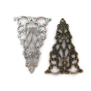 May include: Two ornate metal filigree pendants, one silver and one bronze, with a delicate floral design.