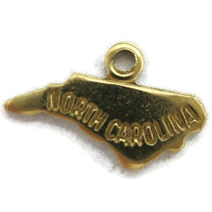 May include: Gold-colored charm shaped like the state of North Carolina with the words "North Carolina" inscribed on it.