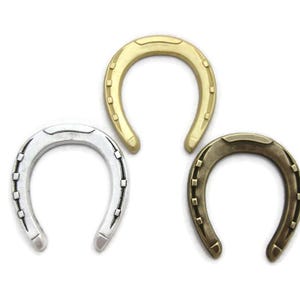 May include: Three metal horseshoes in different finishes: gold, silver, and bronze. Each horseshoe has a traditional design with nail holes.