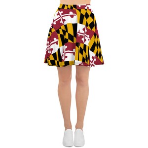 May include: A skater skirt featuring the Maryland state flag design. The skirt has a high waist and a flared silhouette. The flag design includes a mix of red, white, black, and gold colors, with the Maryland state flag's distinctive cross and diamond patterns.