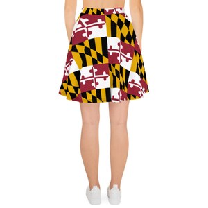 May include: A skater skirt featuring a repeating pattern of the Maryland state flag. The design includes the state flag's colors: red, white, black, and gold. The skirt is a flared style, suitable for casual wear.