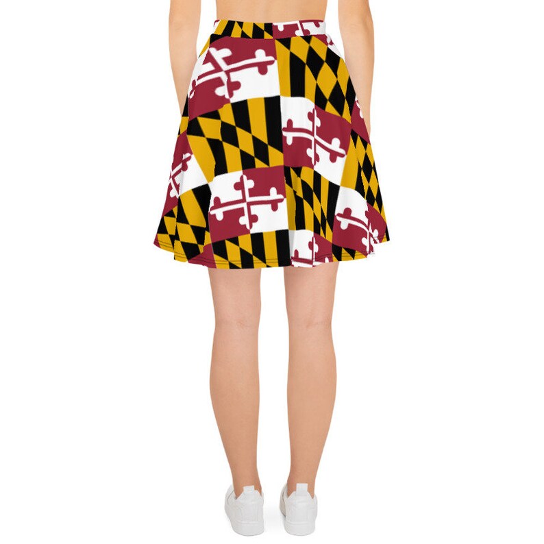 May include: A skater skirt featuring a repeating pattern of the Maryland state flag. The design includes the state flag's colors: red, white, black, and gold. The skirt is a flared style, suitable for casual wear.