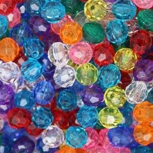 May include: A close-up image of a variety of colorful faceted glass beads. The beads are in various shades of blue, green, red, orange, yellow, purple, and clear. The beads are all approximately the same size and shape.