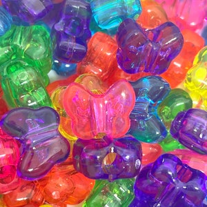 May include: A collection of colorful plastic butterfly beads. The beads are translucent and have a variety of colors, including red, orange, yellow, green, blue, purple, and pink.