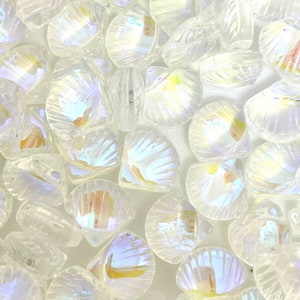 May include: A close-up of iridescent, shell-shaped beads. The clear beads have a textured, ridged surface and reflect a rainbow of colours. These decorative beads are suitable for jewellery making and craft projects.